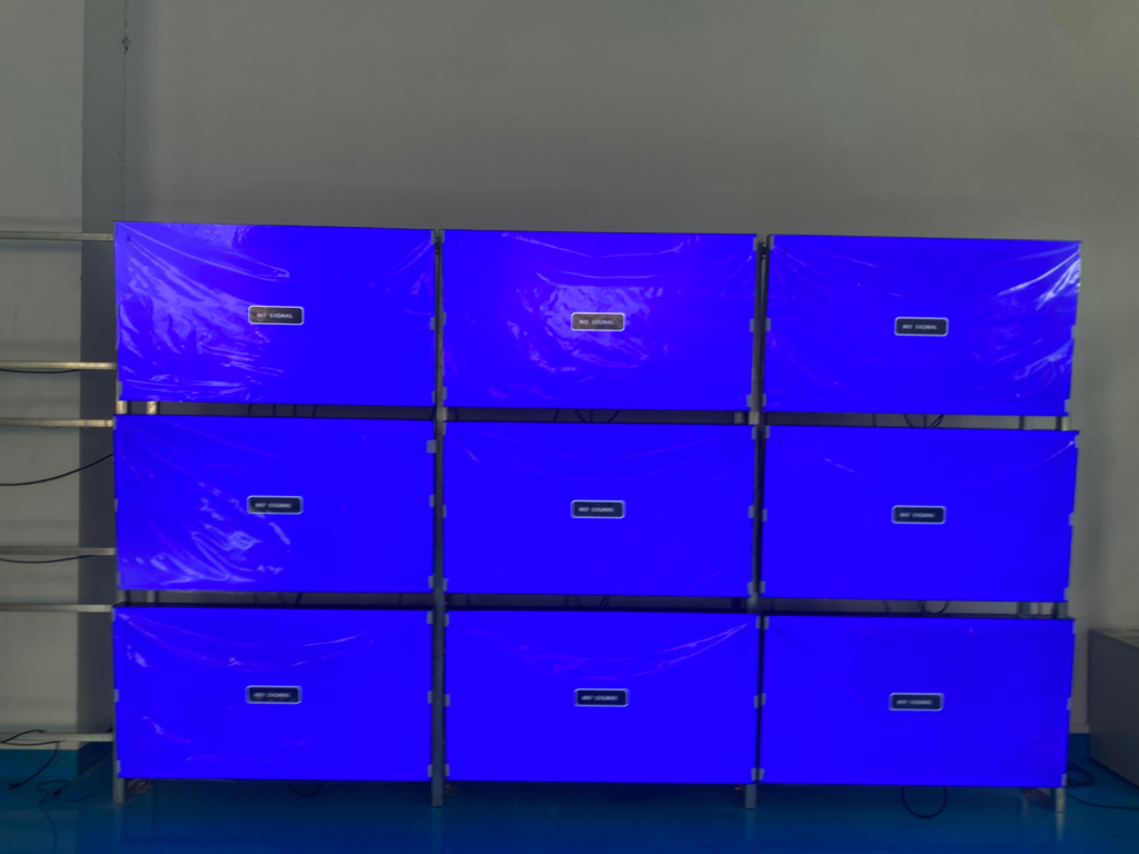 3x3 configuration 55-inch video wall installation with ultra-narrow bezel LCD panels during setup and calibration showing synchronized blue test pattern across nine displays