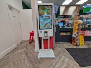 Freestanding self-service ordering kiosk with touchscreen digital menu display in restaurant entrance for contactless ordering