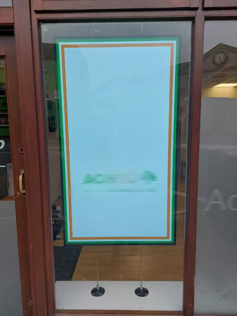 Window display digital signage with transparent LCD screen mounted in retail store glass door showcasing promotional content