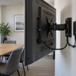 Rear view of a wall-mounted display with a separate media player, accessible connections and space around the bracket.