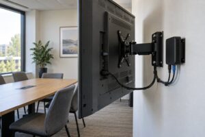 Rückansicht eines wandmontierten Displays mit separatem Mediaplayer, zugänglichen Anschlüssen und Freiraum um die Halterung.