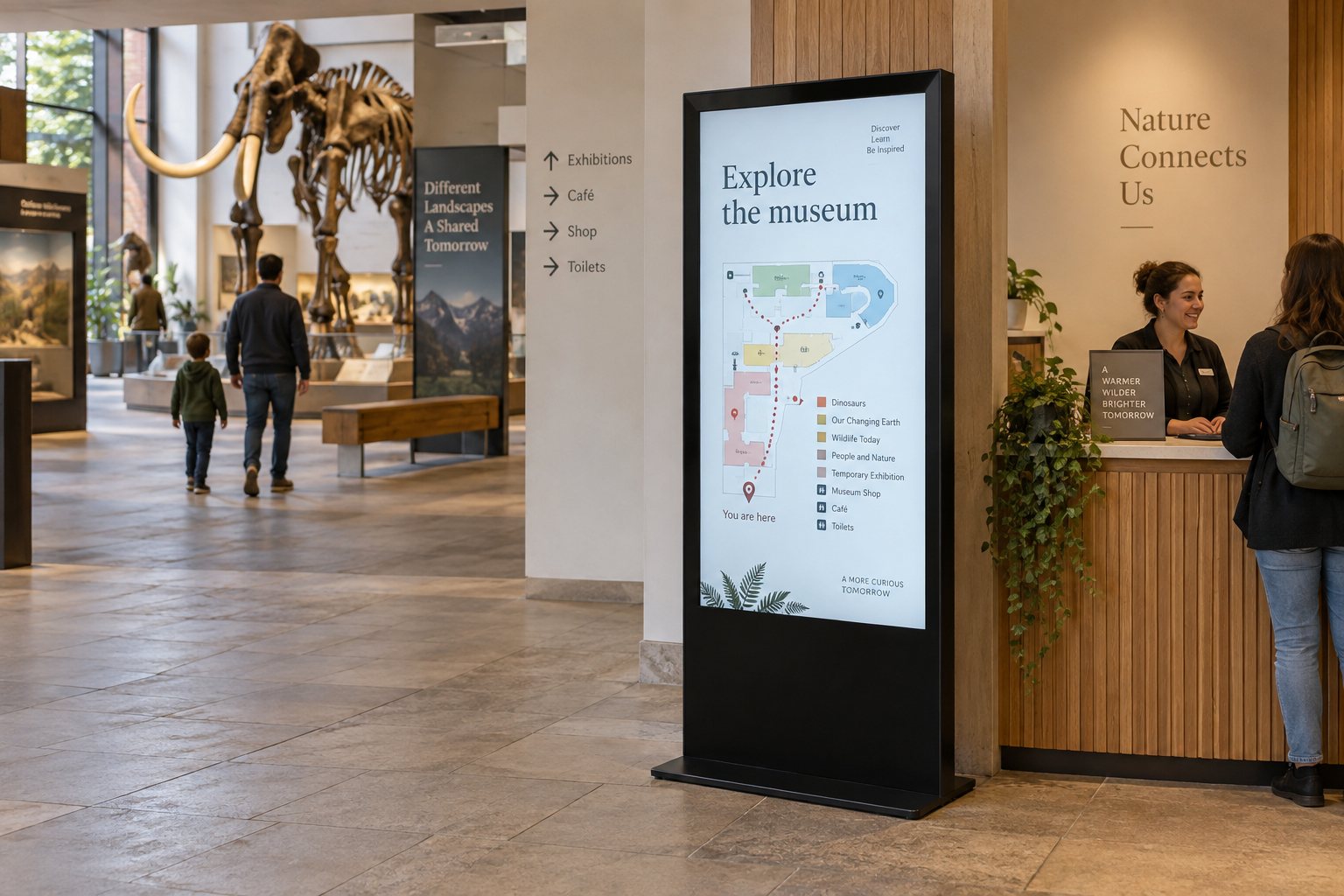 A floor-standing portrait display beside museum reception shows a visitor map and an Explore the museum heading.