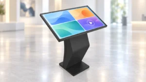Angled landscape touchscreen kiosk on a curved black support and flat rectangular base, displaying four colored interface tiles.
