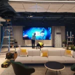 Installatie van een LCD-videowall met vier schermen achter een zetel en een salontafel in een Ierse meubelshowroom.