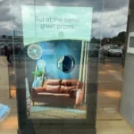 YJCEN 75-inch floor-standing display showing a sofa and furnished-room imagery behind a furniture store window.