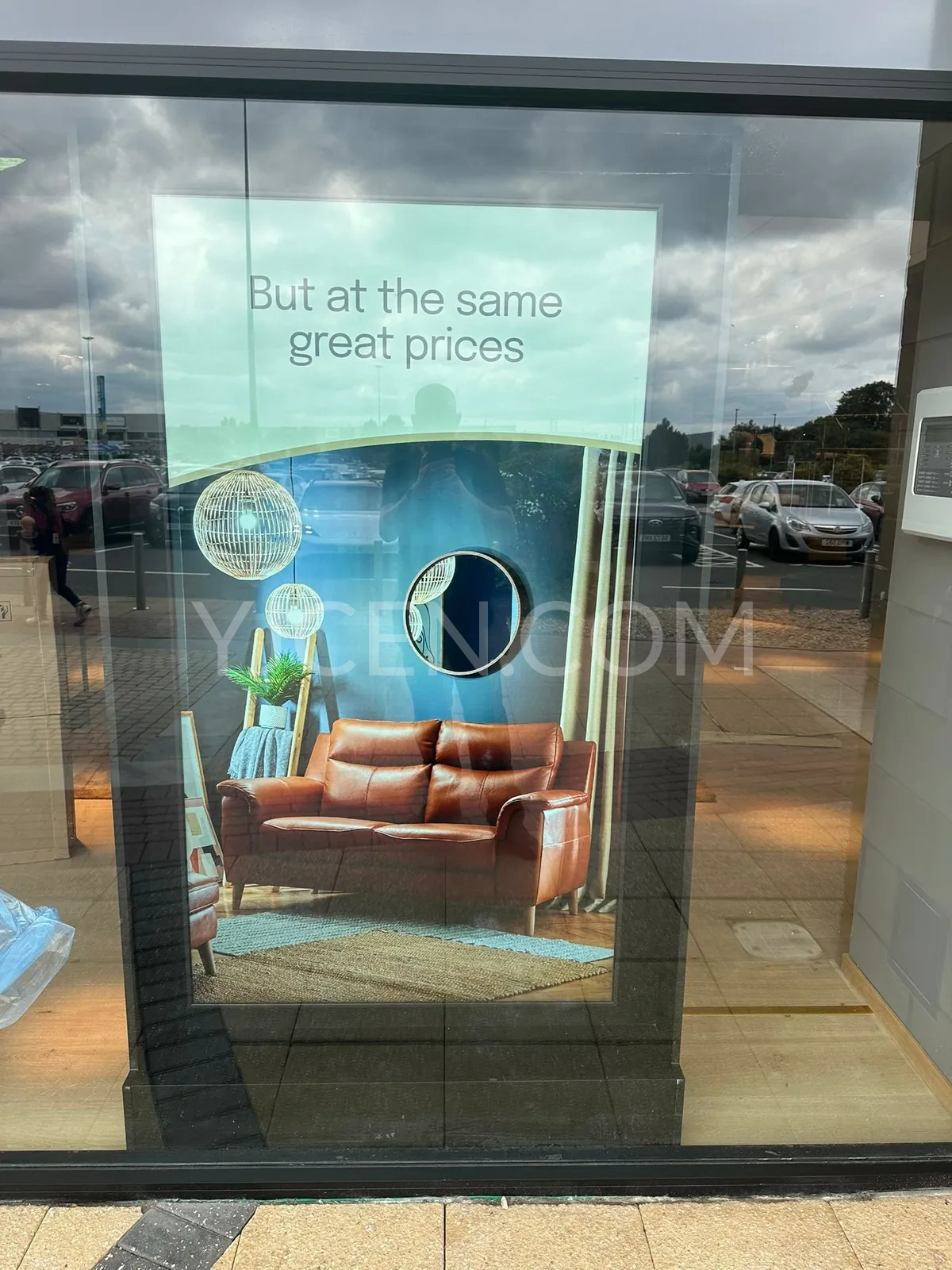 Écran YJCEN sur pied de 75 pouces montrant un canapé dans un intérieur meublé derrière la vitrine d’un magasin de meubles.