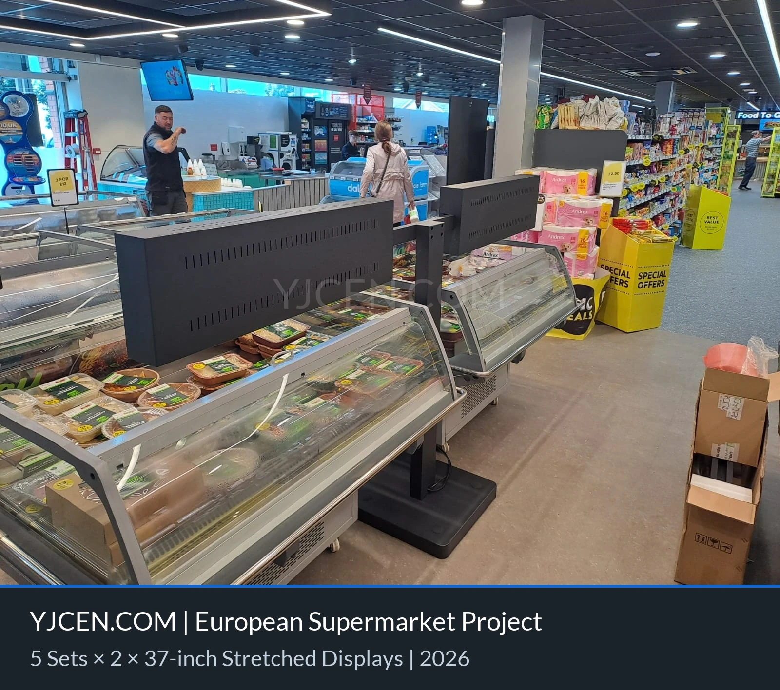 Vista traseira de dois displays em formato de barra e de seu suporte de piso sob medida na área refrigerada do supermercado.