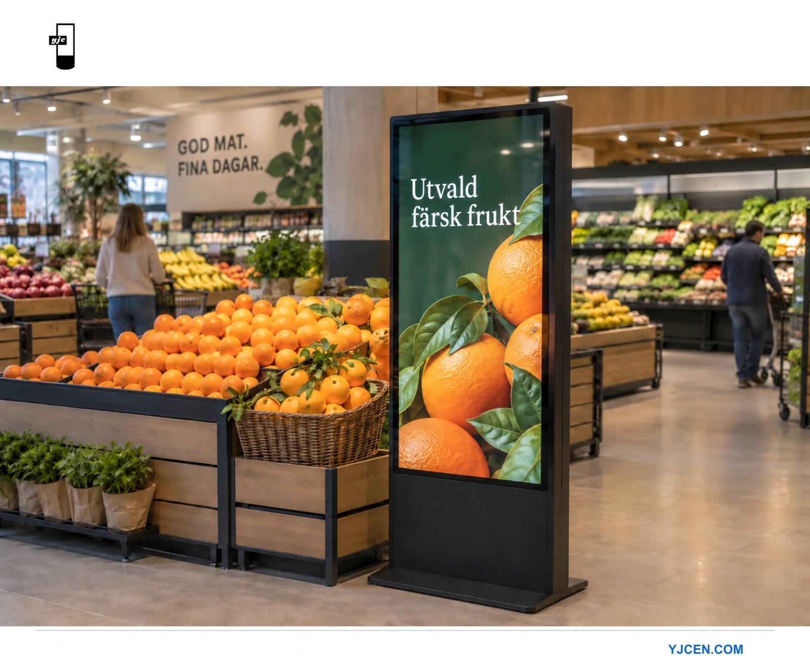 En golvstående reklamskärm bredvid apelsiner i en livsmedelsbutik visar ett budskap om färska varor.